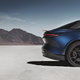 A blue EV sits on a salt flat, with its rear end in the frame of the photo.